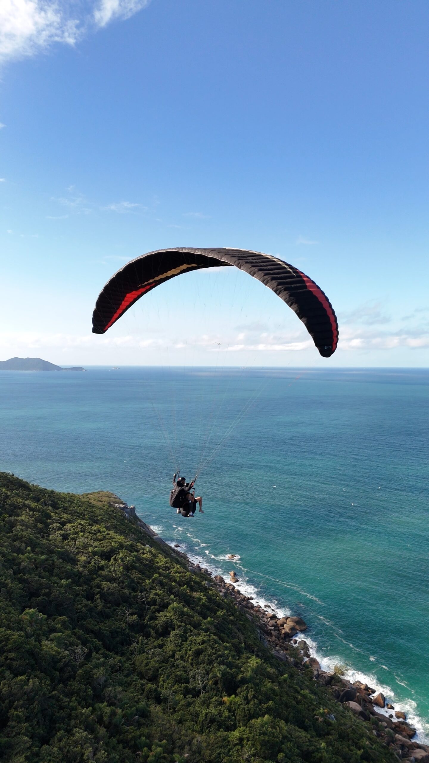 Parapente voando no morro do Rapa na Praia Brava em Florianópolis. Filmagem aérea de drone