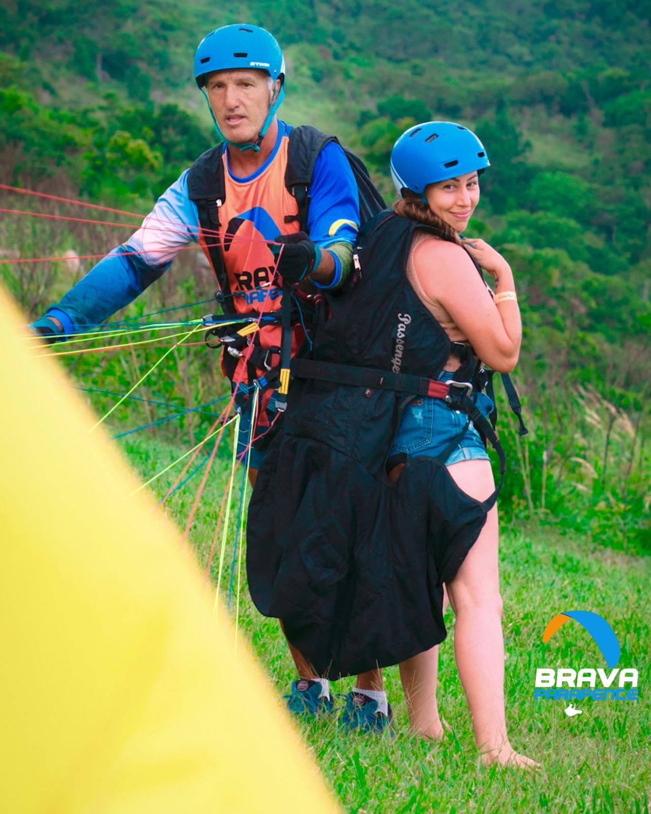 Cliente pronto para o voo duplo de parapente com capacete, sorrindo e animado na decolagem.